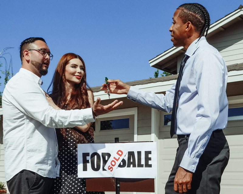 Realtor handing over keys to young couple for their new home